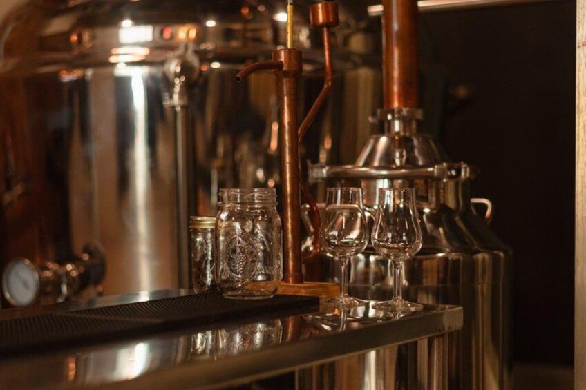 A barista machine with a milk frothing pitcher, a milk jug, and a few glasses. 2
