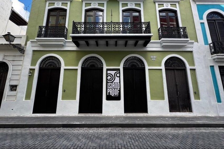 A building with green and white facades, black shutters, and a sign that reads 'ISLAND PROOF.' 3