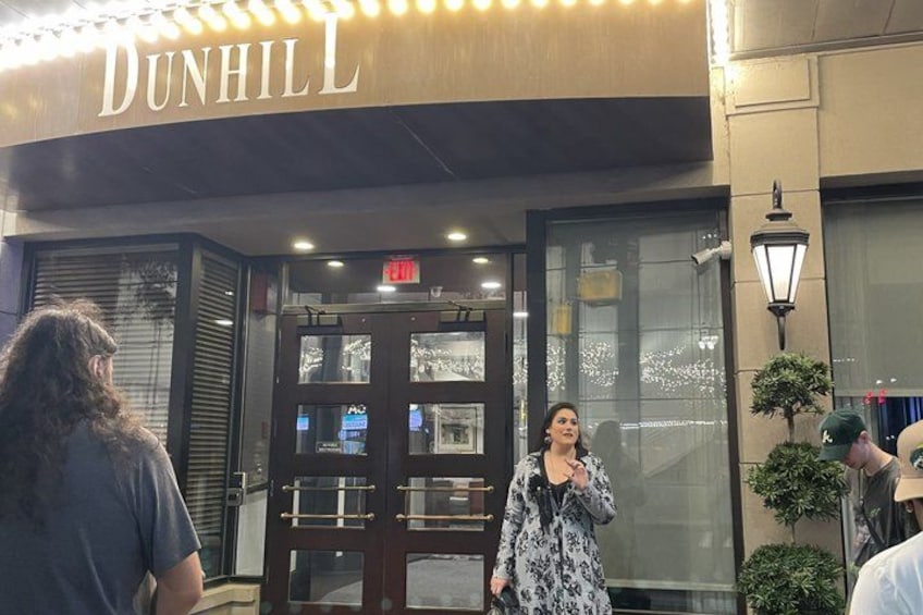 The exterior of Dunhill building with a glass door entrance, a sign above the door, and a street lamp to the right. 2