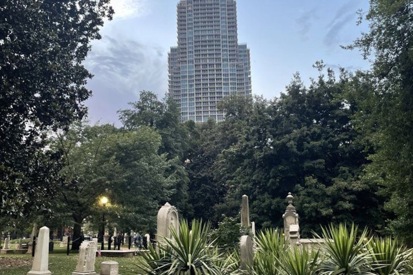 A cemetery with headstones and a tall building in the background. 1