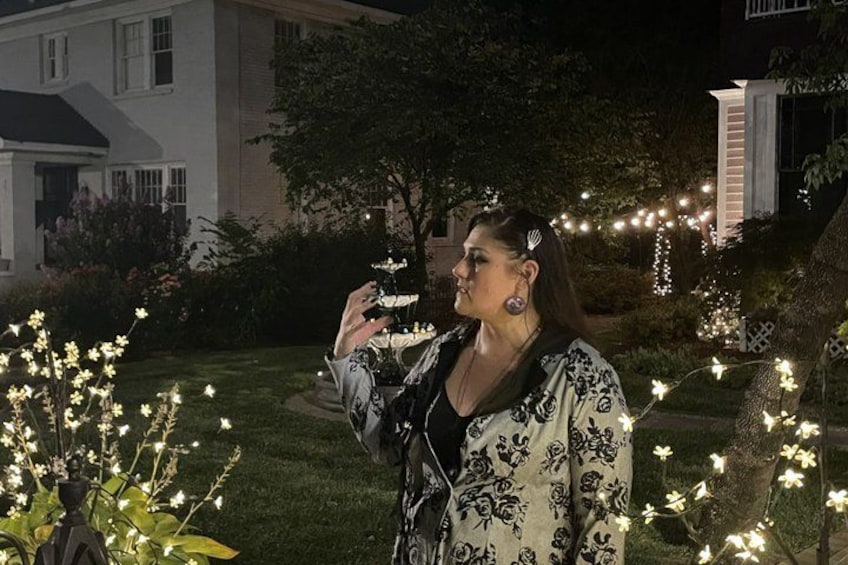 A person standing in a garden at night with string lights. 5