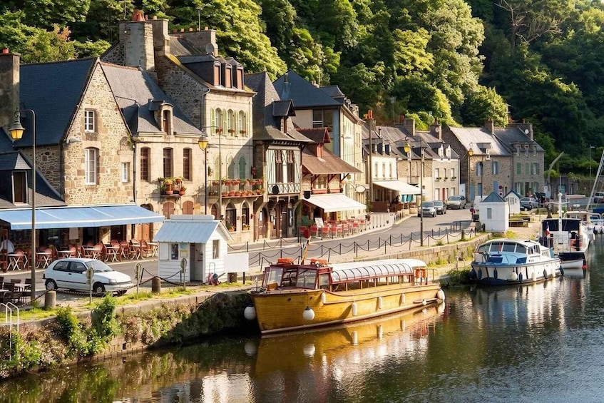 A riverside town with historic buildings, a yellow boat docked, and a café with outdoor seating. 3