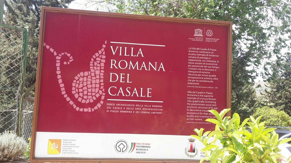 A signboard with the text 'Villa Romana del Casale' and a mosaic of a camel. 5