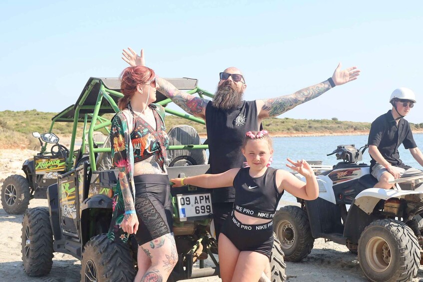 A group of people on a beach with ATVs and a dune buggy. 3