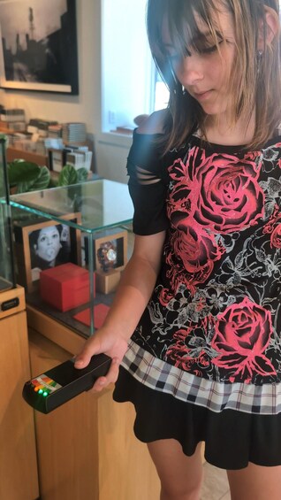 A person holding a remote control with a red button. 5