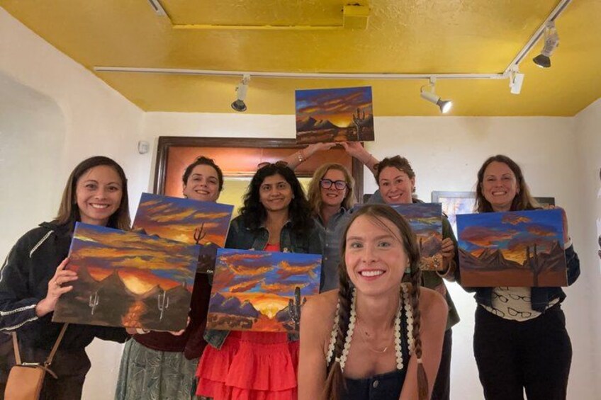 A group of people holding up paintings of landscapes. 1