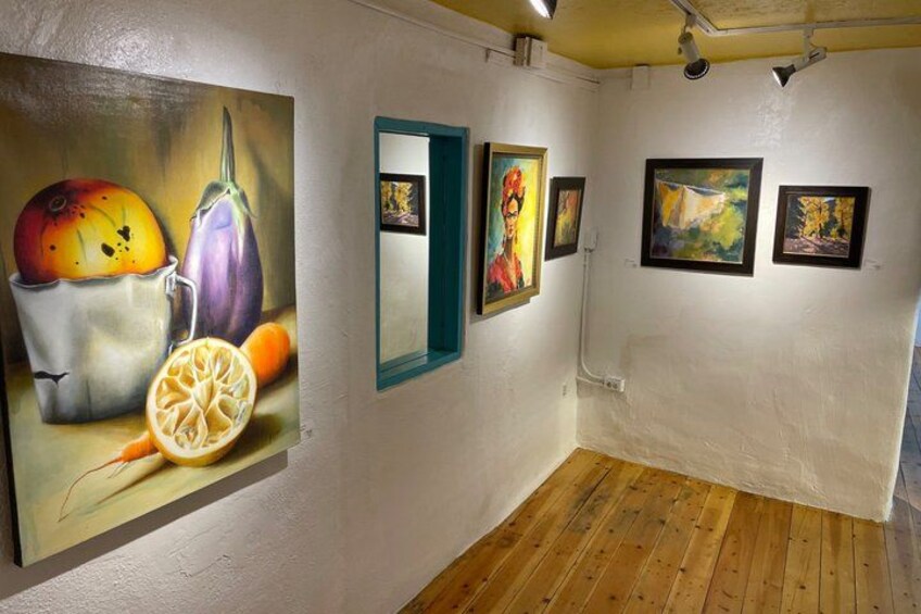 An art gallery with paintings on the walls and a wooden floor. 4