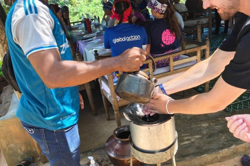 A person pouring liquid from a metal container into a bowl. 3