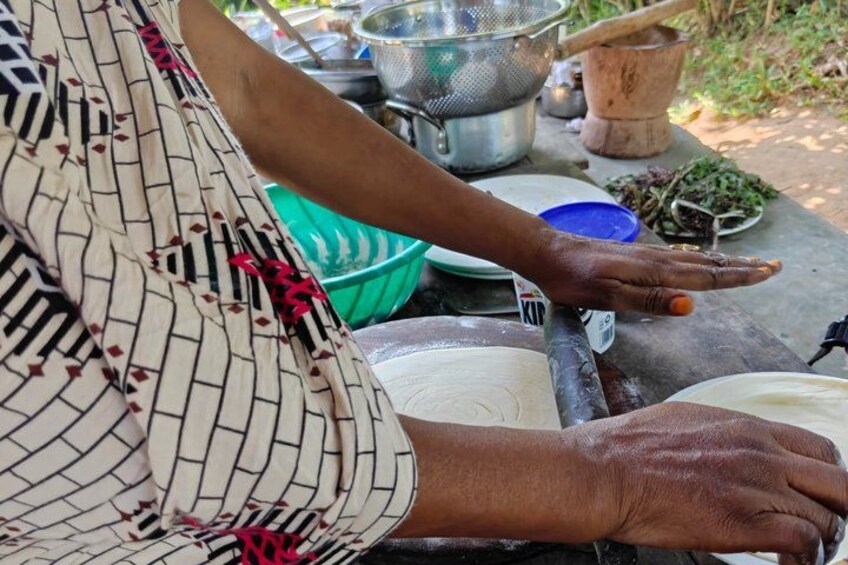 A person preparing food, with a bowl, a plate, and a metal container on the table. 2