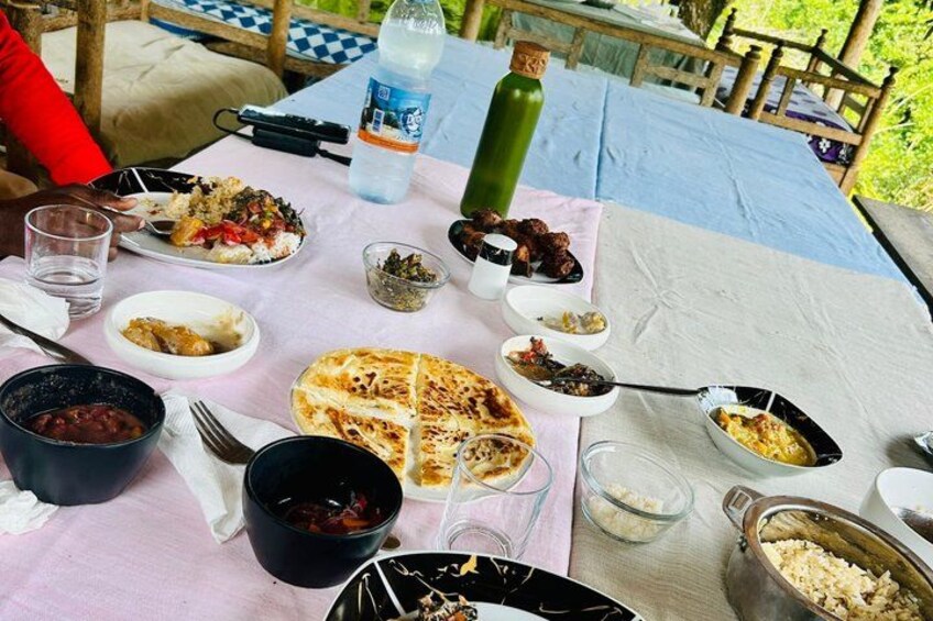 A picnic table with various dishes, including a grilled cheese sandwich, bowls of food, and a bottle of water. 5