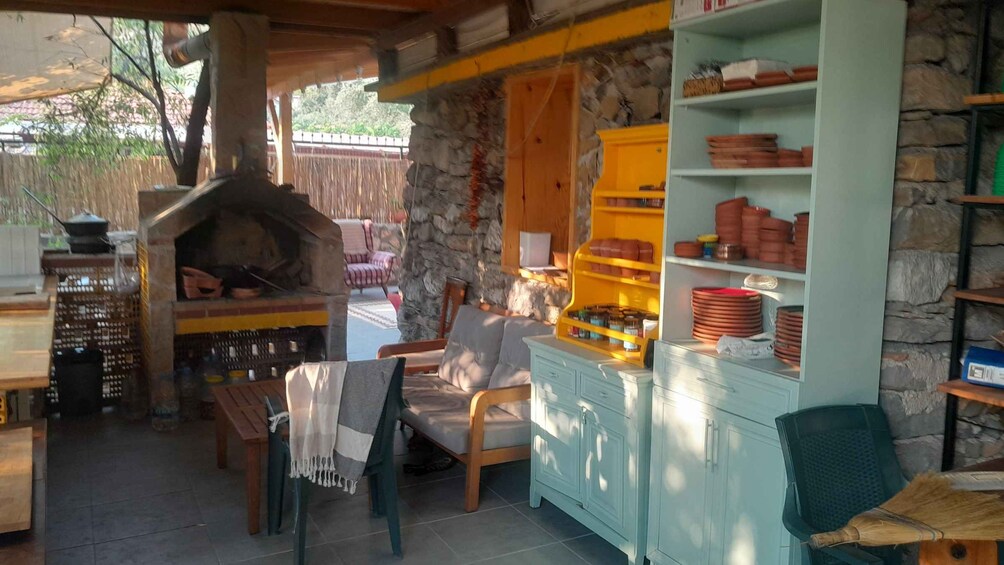 Una cocina rústica al aire libre con pared de piedra, muebles de madera y horno de ladrillo. 3