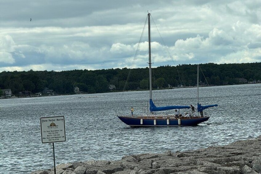 A sailboat on a calm body of water with a sign indicating Stone Harbor Marina. 2