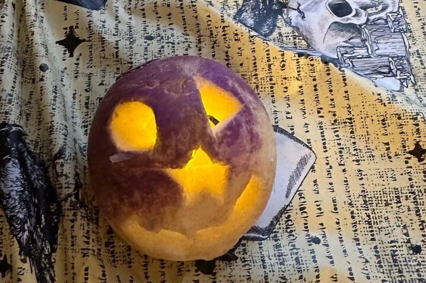 A carved pumpkin with a star-shaped cutout, placed on a patterned fabric background. 5