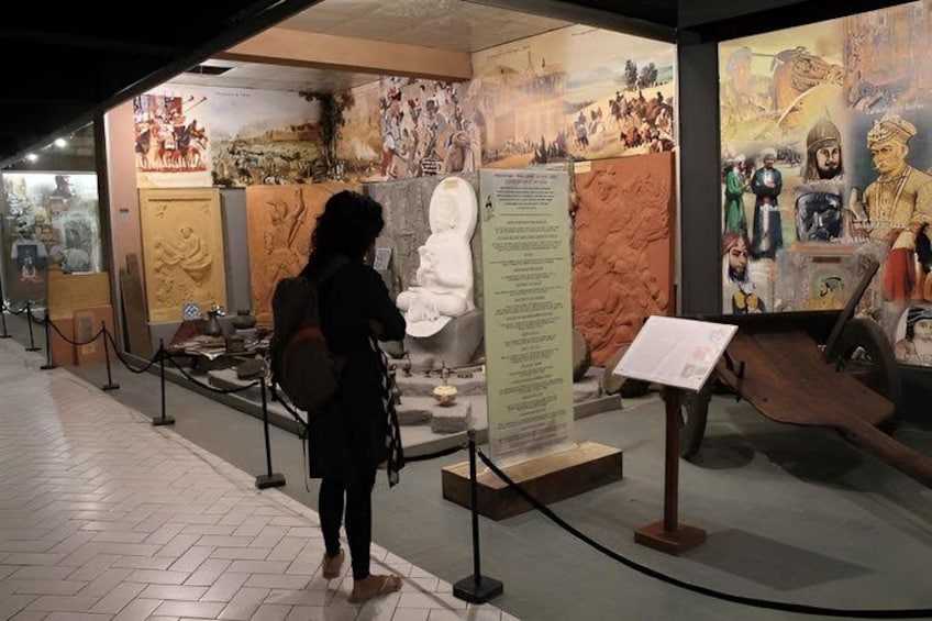 A museum exhibit with a large white statue, informational panels, and historical artifacts. 5