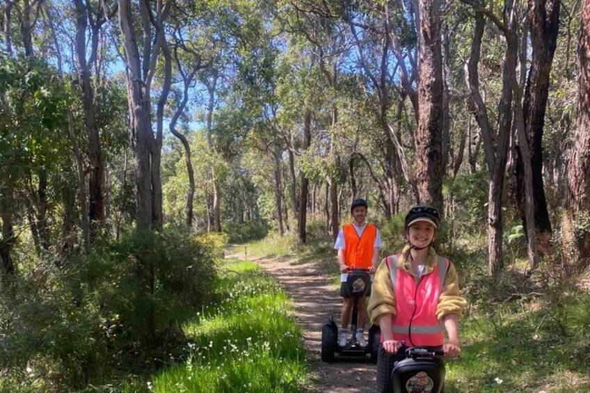 Two people on a forest trail, one on a scooter and the other on a bicycle. 3