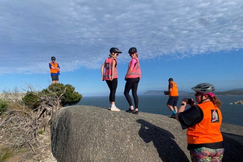 A group of people on a rocky outcrop overlooking a body of water. 4