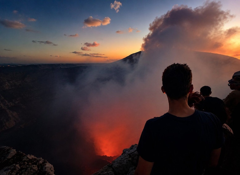 A volcanic landscape with a lava flow and a group of people observing. 1