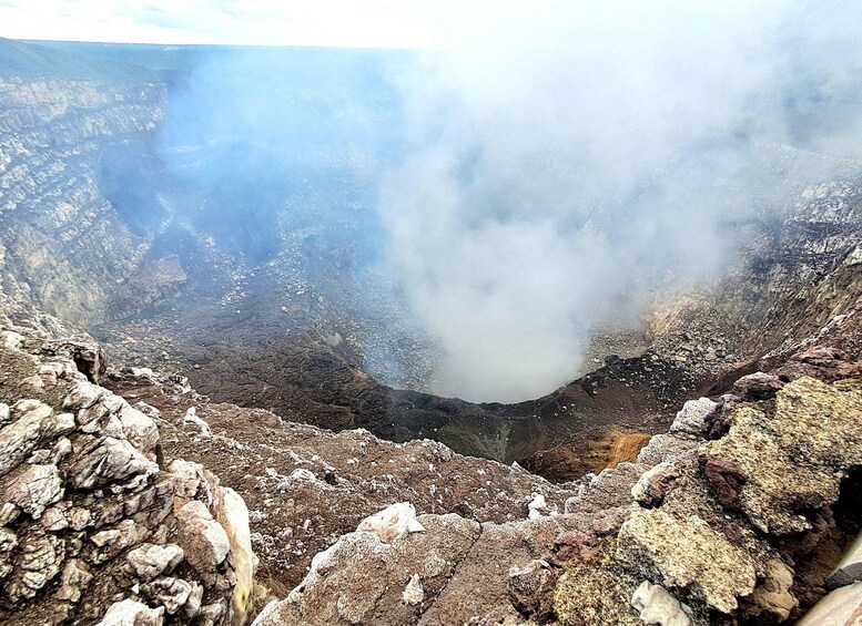 A volcanic crater with a central pool of water, surrounded by rocky terrain and emitting steam. 4