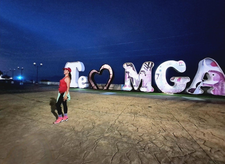 A person standing in front of large, colorful letters spelling 'TeMGA' with a heart shape in the middle. 5