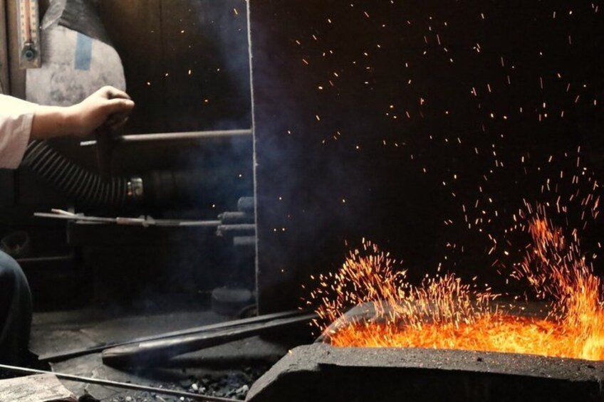 Sparks flying from a welding process, a person operating a welding machine, and a metal workbench. 3