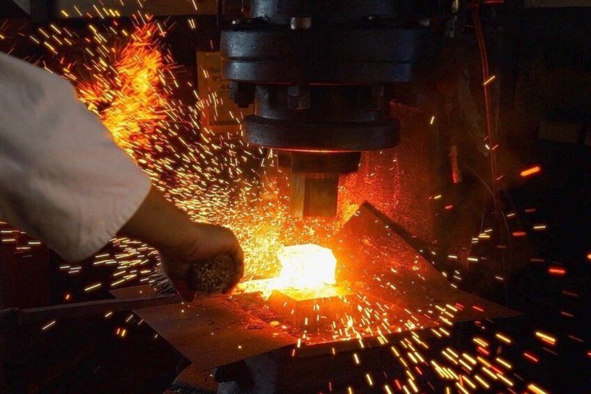 A person operating a machine that is cutting or shaping metal with sparks flying. 1