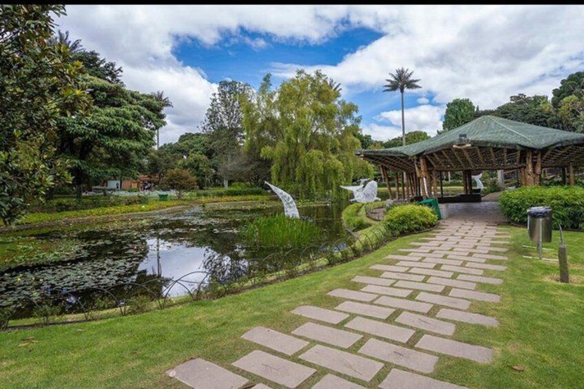 A garden with a pond, a gazebo, and a stone pathway. 2