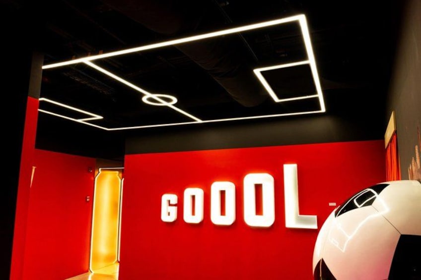A red wall with the word 'GOOOL' in white letters, a white car, and a modern ceiling with geometric light fixtures. 4
