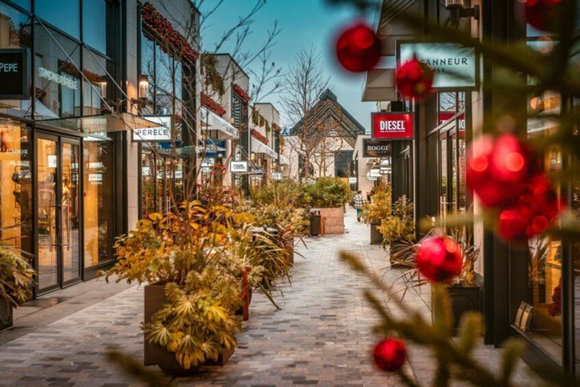 Une rue commerçante bordée de boutiques, agrémentée de plantes en pot et décorée de rouge. 2