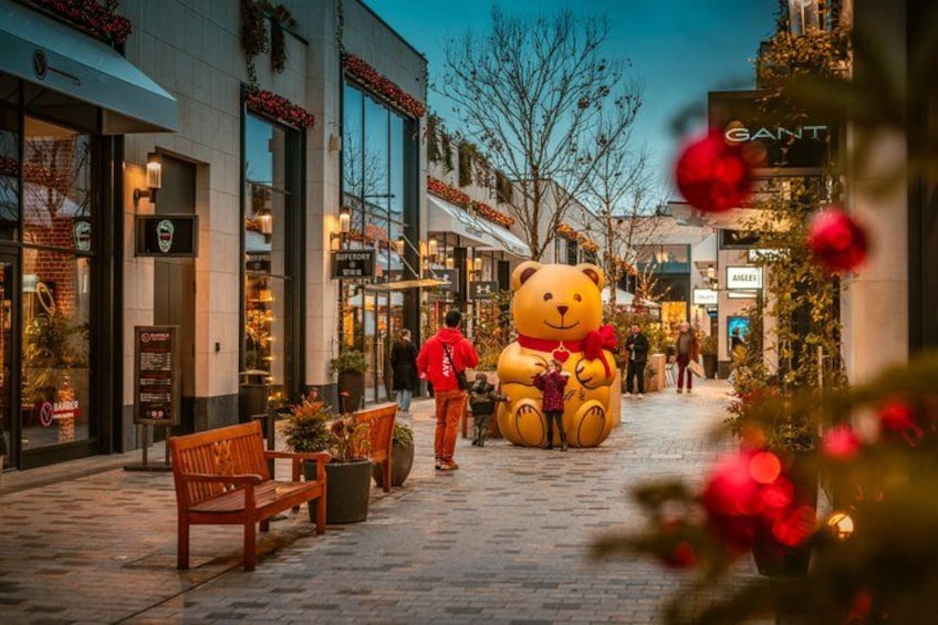Un espace commercial agrémenté d’une grande statue d’ours en peluche, de bancs et de décorations de Noël. 3