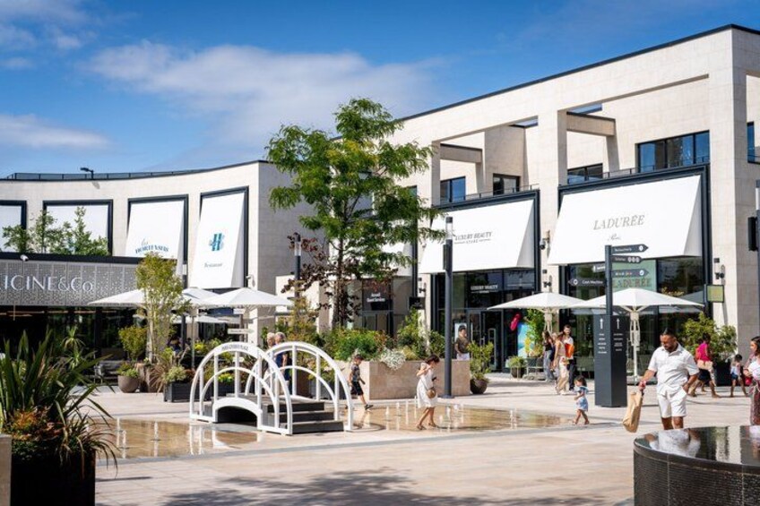 A modern shopping center with outdoor seating and a fountain. 3