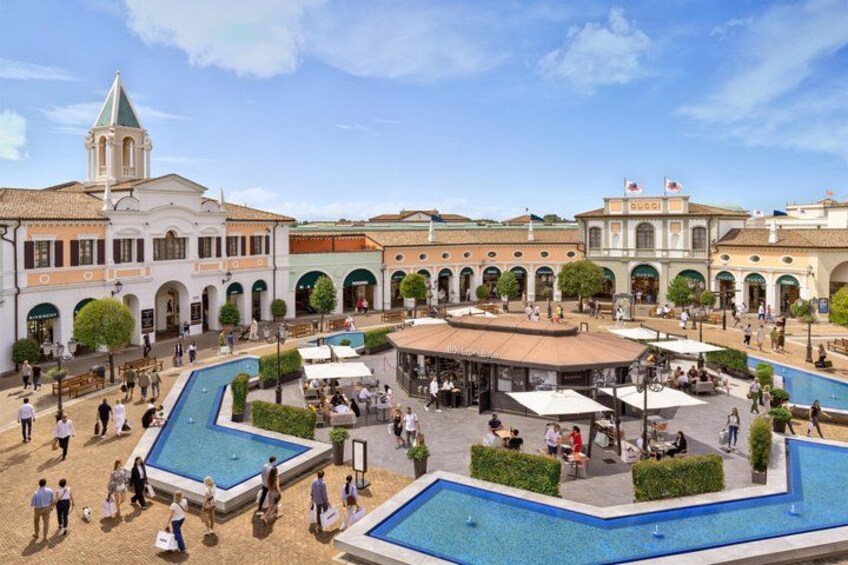 A public square with a central fountain, surrounded by buildings with arches and a pool. 4