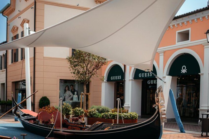 A gondola, a tree, and storefronts with 'GUESS' branding. 5