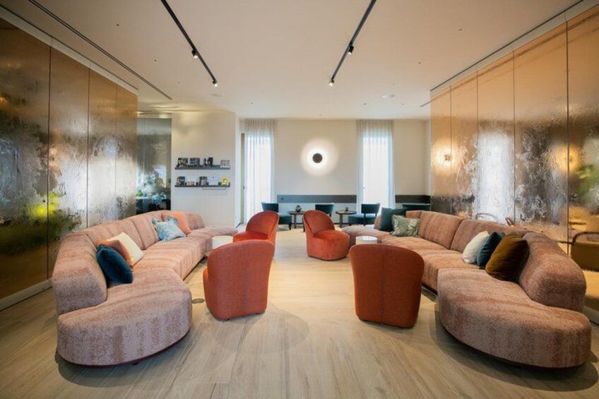 A modern living room with a pink sectional sofa, orange armchairs, and a wooden floor. 1