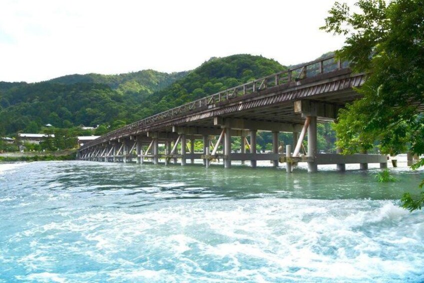 A wooden bridge over a river with a forested hillside in the background. 5