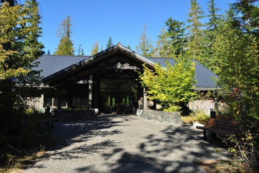 A lodge with a covered entrance, surrounded by trees and a gravel path. 5