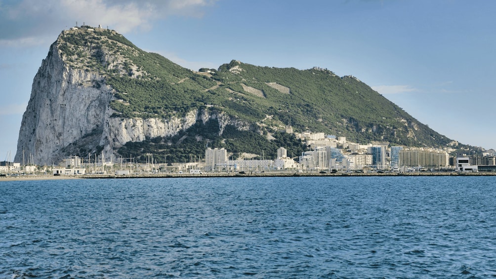Eine Küstenstadt mit einem markanten Berg und einem Yachthafen. 1