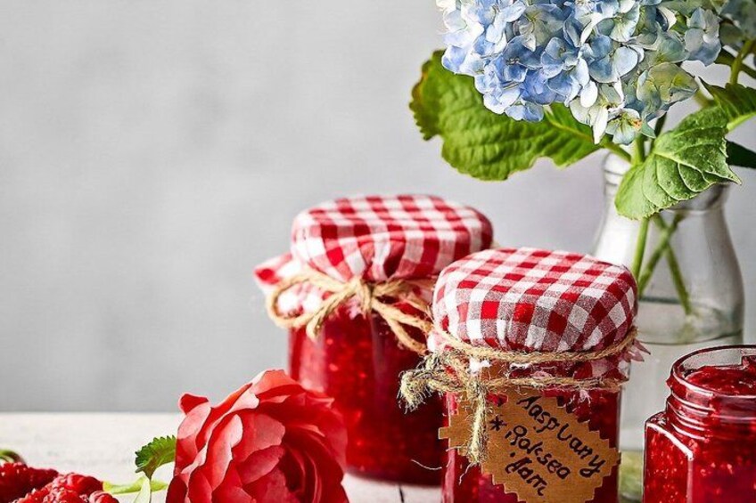 Two jars with red lids and handwritten labels, a red rose, and a vase with blue hydrangeas. 3
