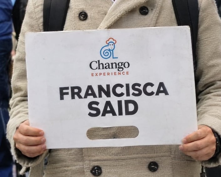 A person holding a sign with the text 'Francisca Said' and the logo 'Chango Experience'. 1