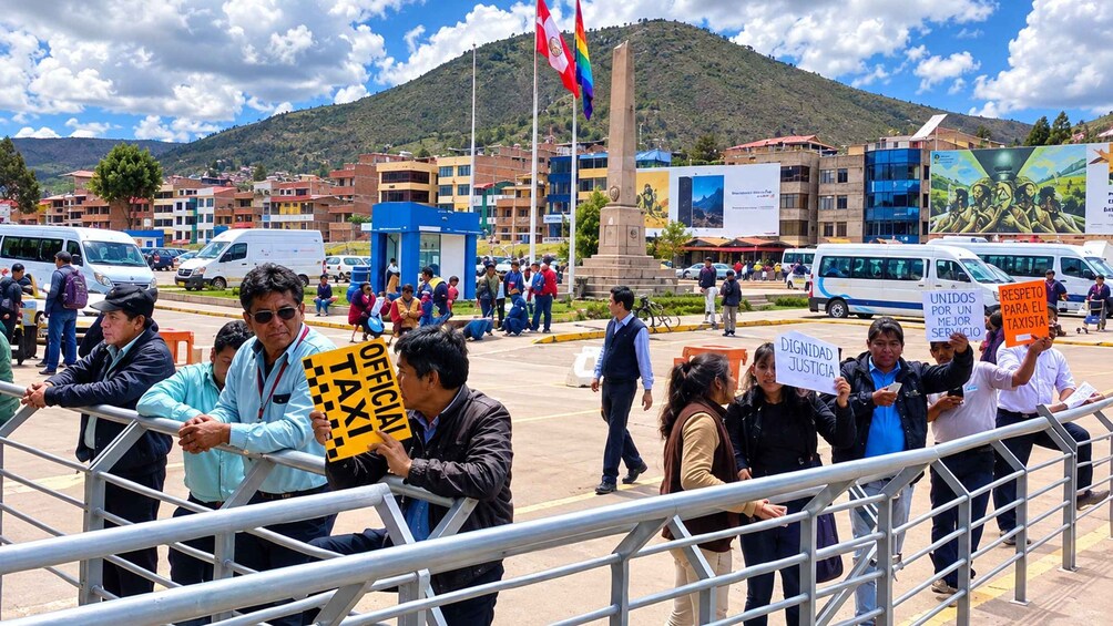 A public demonstration with people holding signs and a mountainous backdrop. 3