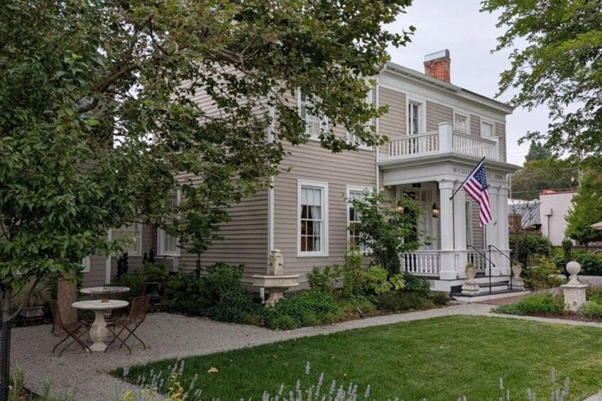 A two-story house with a porch, a flag, and a well-maintained lawn. 2