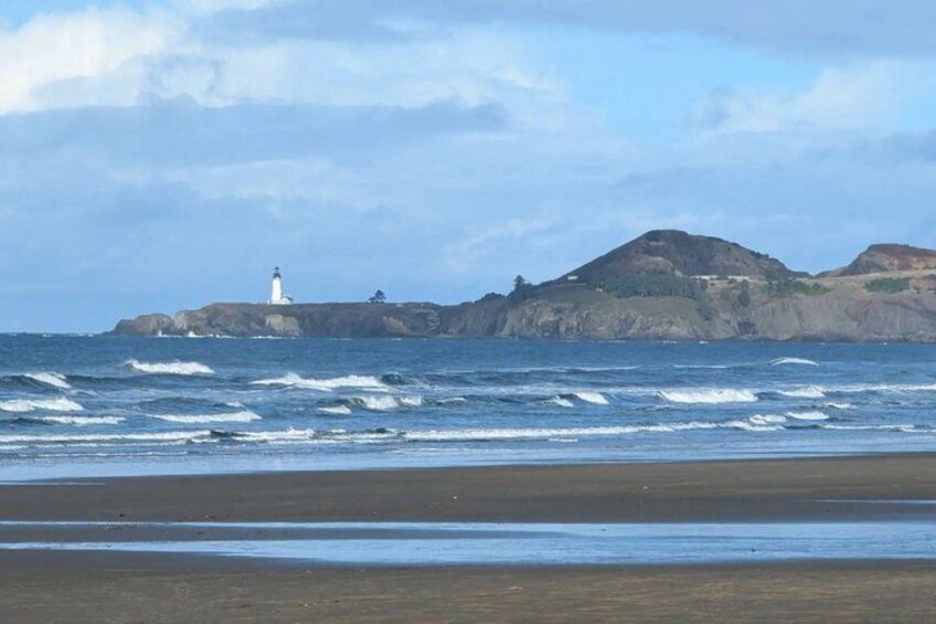A beach with waves, a lighthouse, and rocky cliffs. 4
