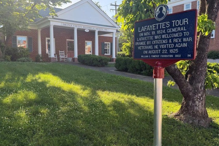 A brick building with a signboard and a tree in front. 4