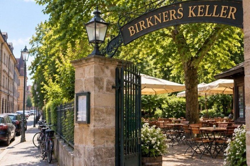 A restaurant entrance with outdoor seating, a bicycle, and parked cars. 2