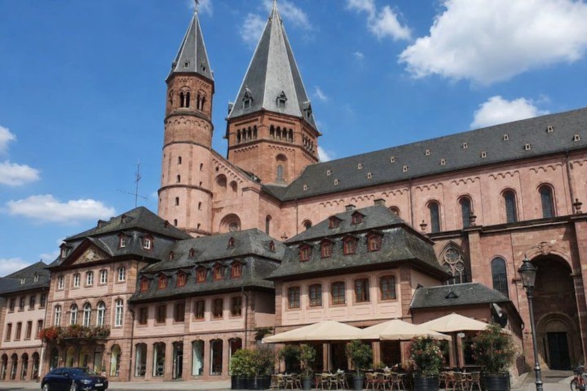 A historic building with two prominent towers and a courtyard with outdoor seating. 5