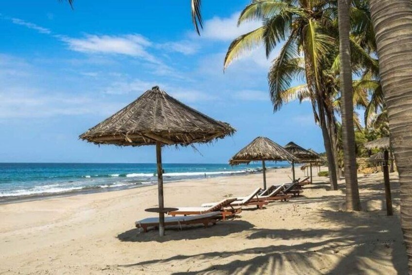 A beach with thatched umbrellas and lounge chairs. 2