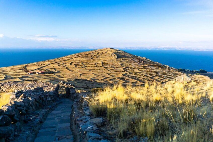 A terraced landscape with ruins and a clear view of the sea. 5