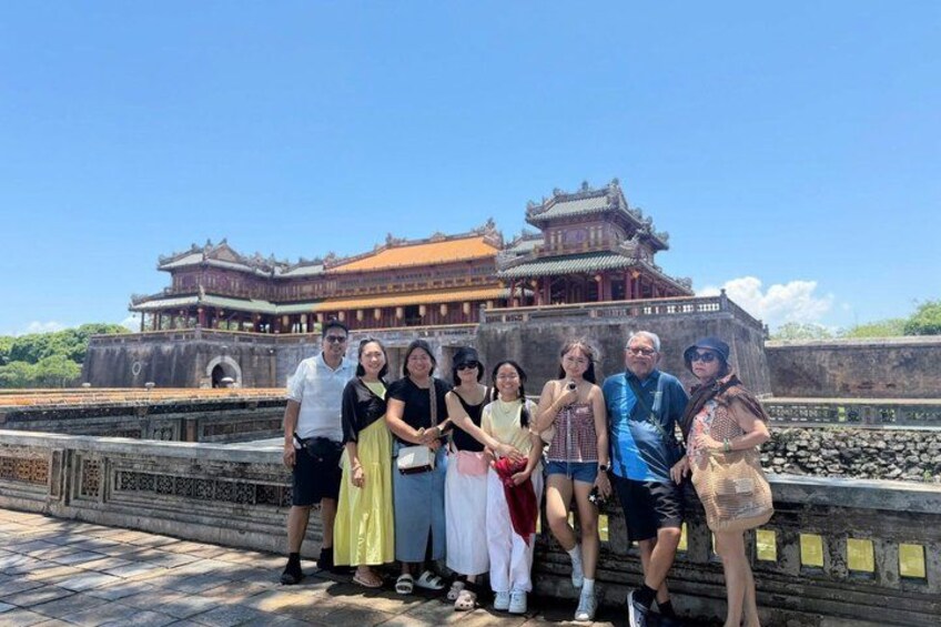 A group of people posing in front of a traditional Chinese building with a red roof and ornate architecture. 1