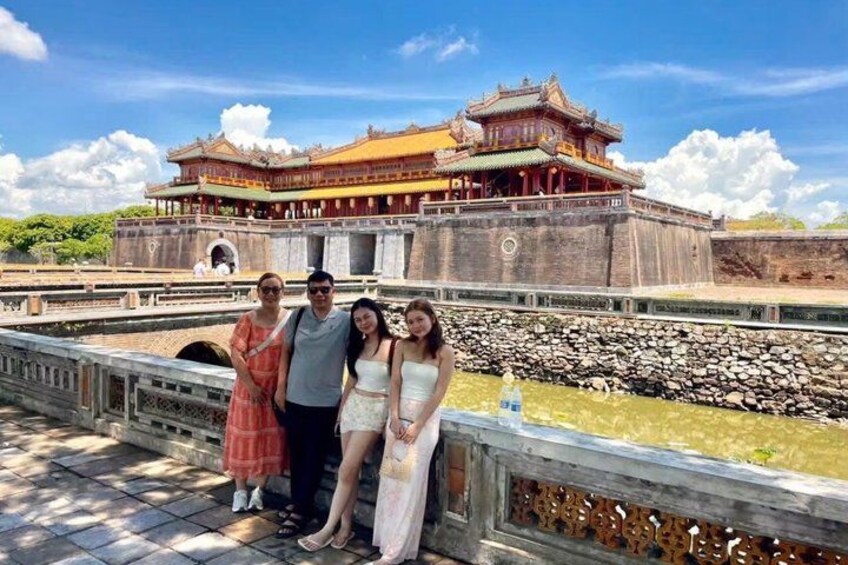 A group of people standing in front of a traditional Chinese building with a large courtyard and a stone wall. 3