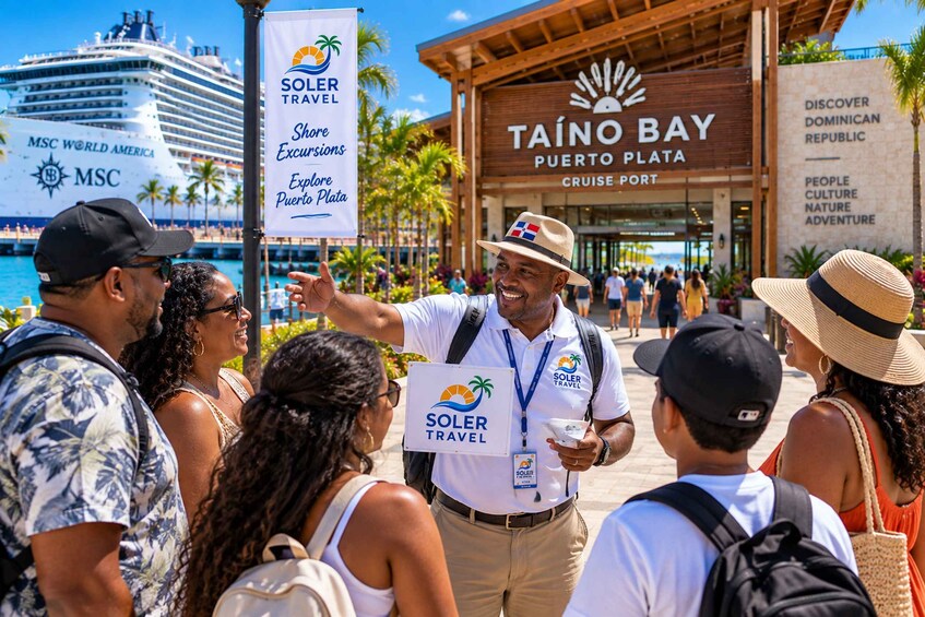 A group of people at a travel agency, with a banner for Soler Travel and a sign for Taño Bay Puerto Plata Cruise Port. 4
