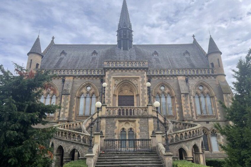 A large, historic building with a prominent tower, arched windows, and a grand staircase. 5